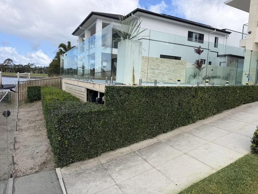 Long box hedge trimmed level along a waterfront home — hedge trimming Northern Gold Coast